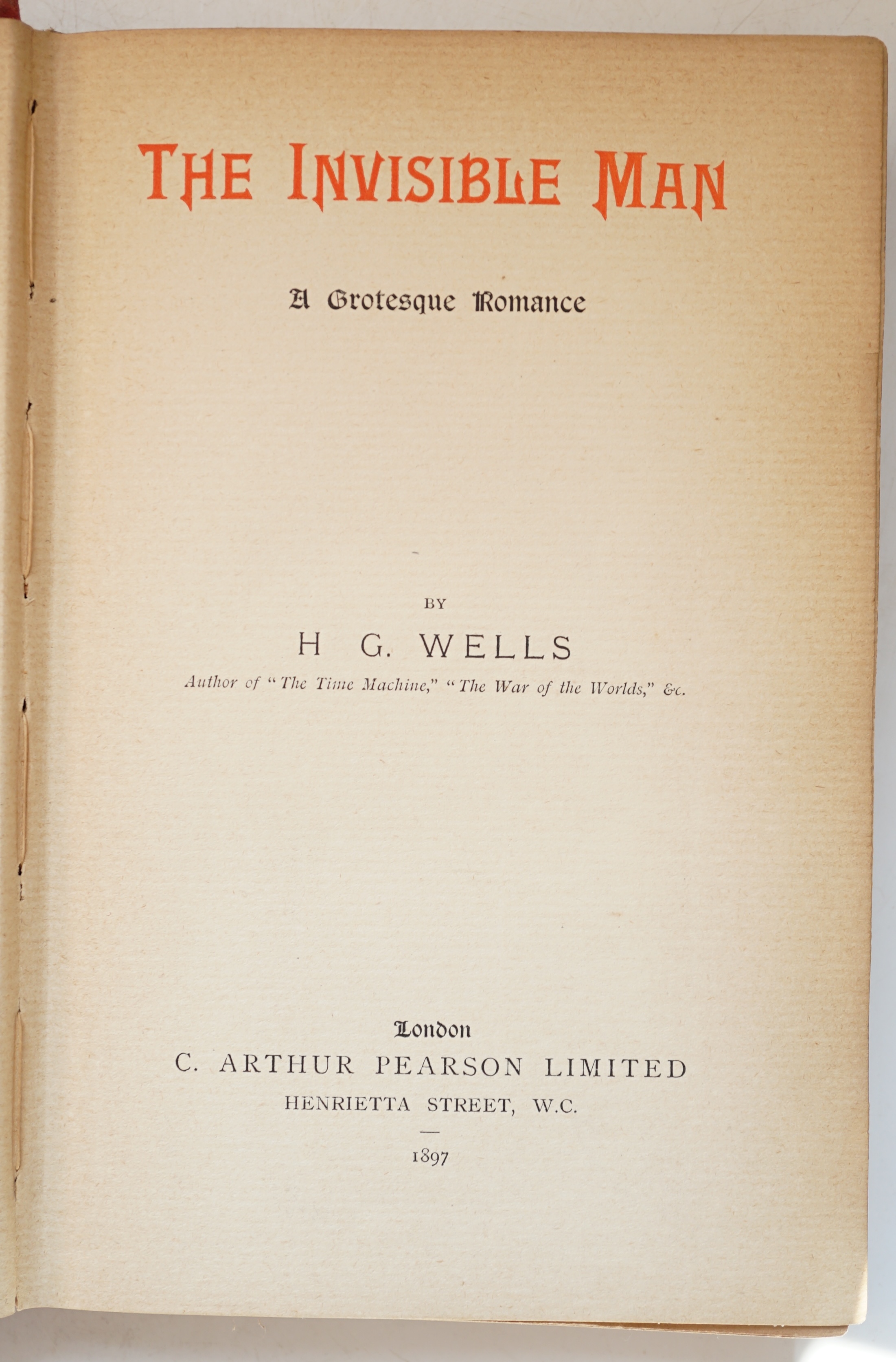 Wells, H. G. (1866-1946). The Invisible Man. A Grotesque Romance, 8vo, half title, title printed in orange and black, 2-pages of publisher's advertisements at the end, original red pictorial cloth lettered in gilt, light